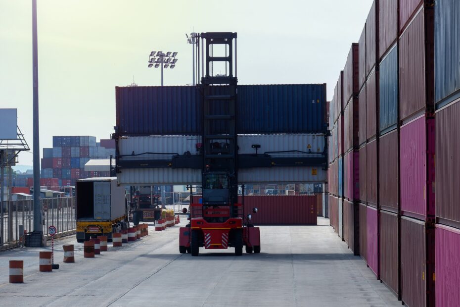 Bilden visar en truckförare av en stor truck i ett område med containrar. Med en truckutbildning i Göteborg kan du få en truckförarutbildning på truckar som används på stora industrier samt vid annan typ av lossning som exempelvis containerlossning.